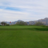 A view of a green with mountains in the distance at Painted Dunes Desert Golf Course.
